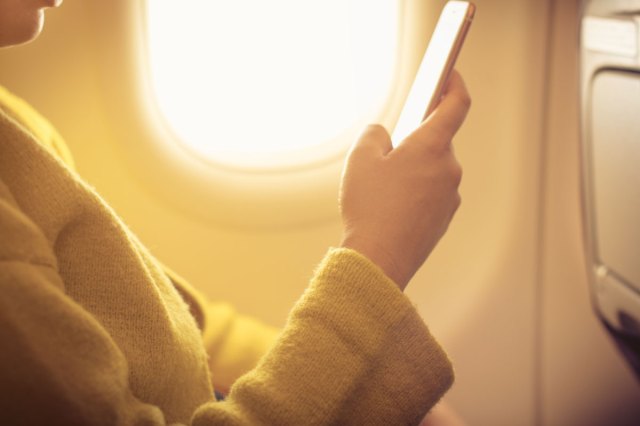 A person on an airplane checks their phone