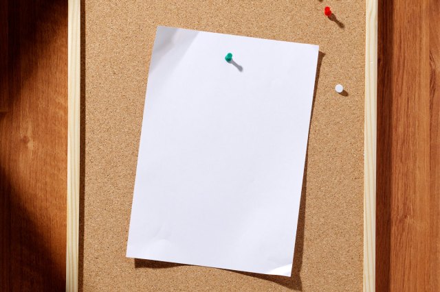 An image of a white piece of paper tacked onto a bulletin board