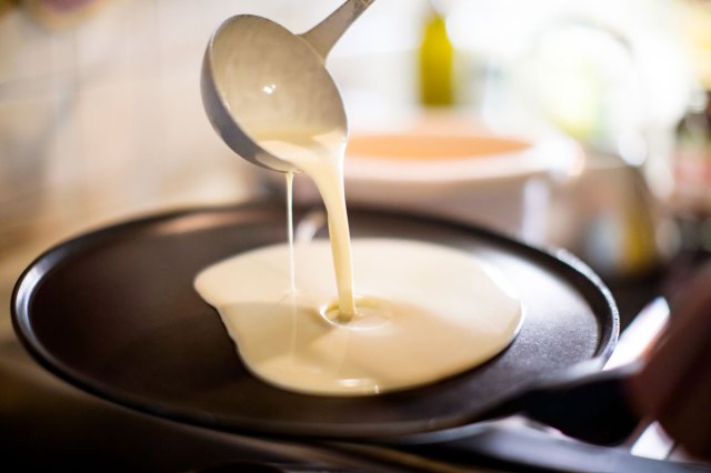 An image of pancake batter being ladled onto a pan