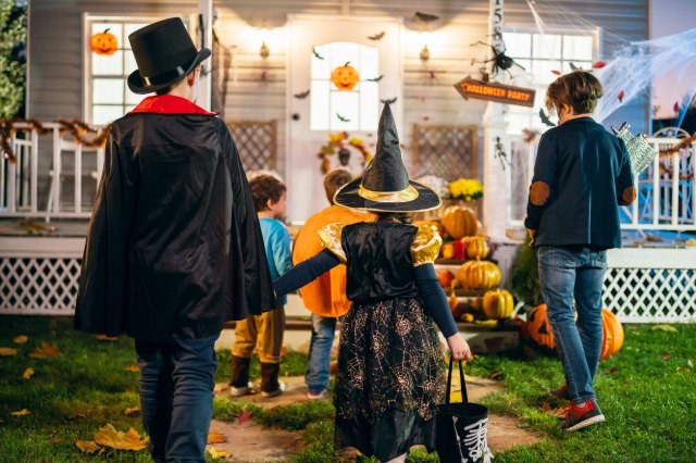An image of kids in Halloween costumes walking up to a house