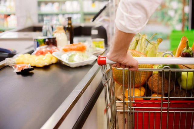 An image of a person with a shopping cart in the checkout aisle