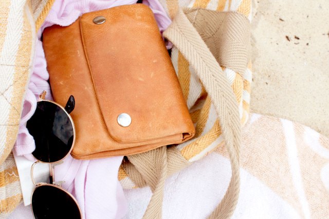 An image of a brown leather shoulder bag with dark sunglasses