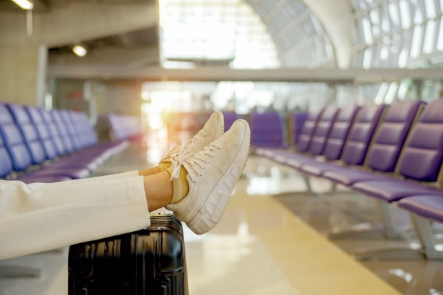 A person puts their feet up on their luggage in an airport waiting area