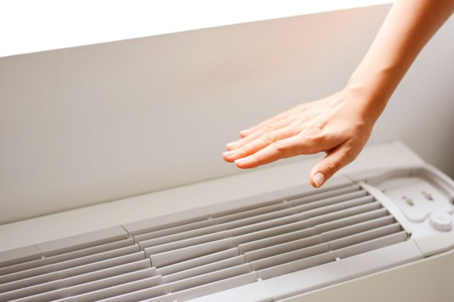 An image of a hand hovering over an air conditioning unit