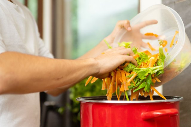 An image of a person pouring vegetables into a red pot