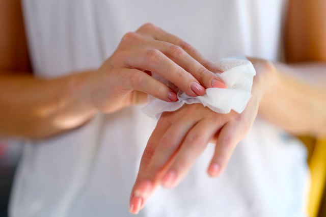 A person wipes the back of their hand with a white cloth