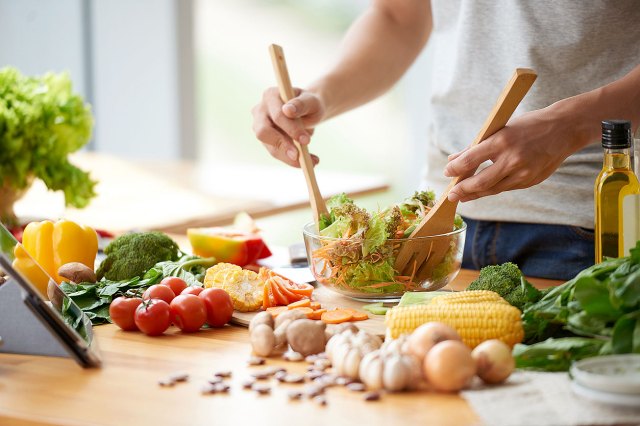 An image of a person tossing a salad with vegetables all over the counter