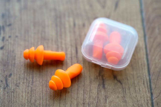 A pair of neon orange ear plugs on a wooden surface