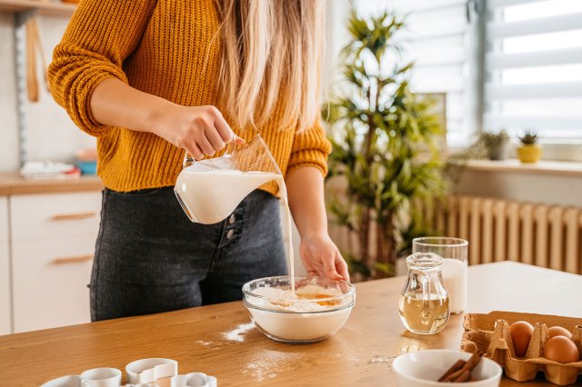 An image of a woman pouring milk into a mixing bowl