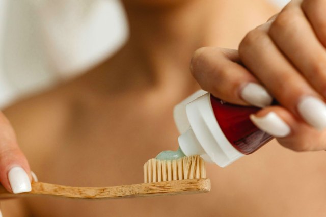 An image of a person putting toothpaste onto a toothbrush