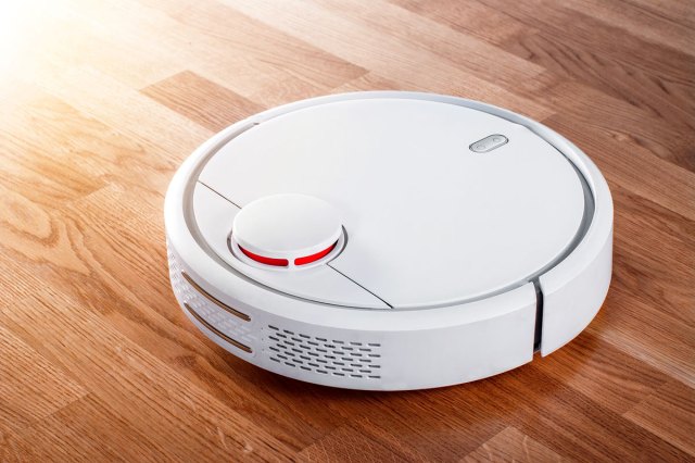 An image of a white robotic vacuum on a wood flood