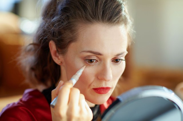 An image of a woman putting concealer under her eye