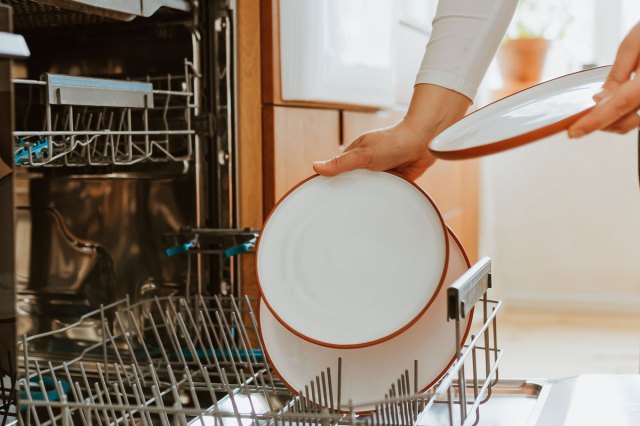 An image of a person loading dishes into the dishwasher
