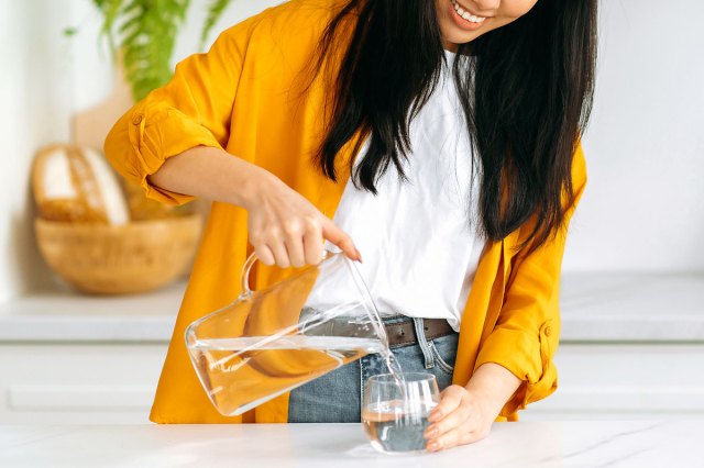 An image of a woman pouring a glass of water