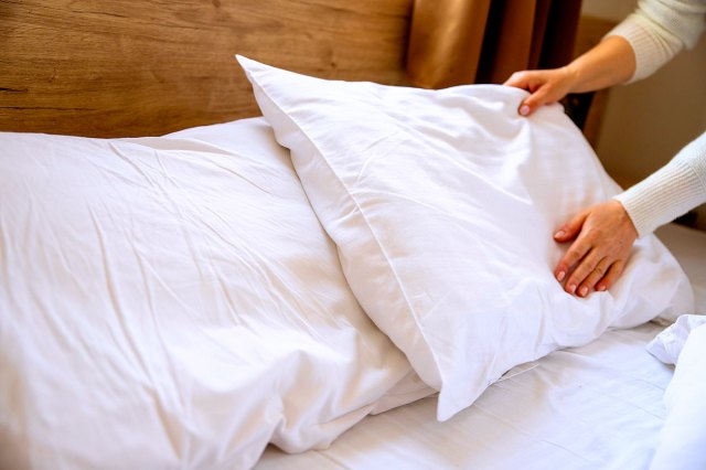 An image of a person putting a pillow on a bed
