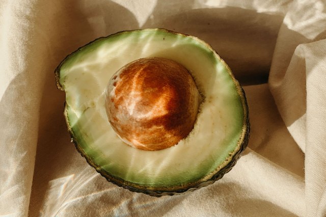 An image of a half of an avocado with the pit