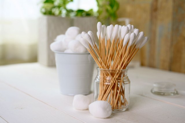 An image of cotton swabs in a jar next to a small bucket of cotton balls