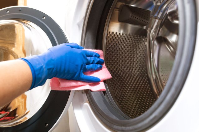 An image of a person wiping a washing machine down