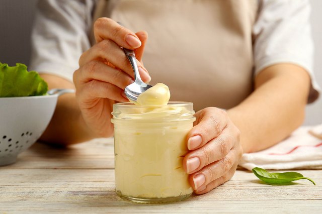 An image of a person spooning mayonnaise out of a jar