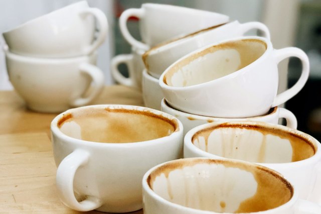 An image of stacked dirty coffee mugs