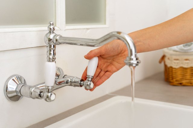 An image of a person turning on a bathtub faucet