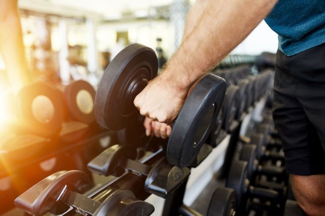 An image of a man taking a free weight off a weight rack