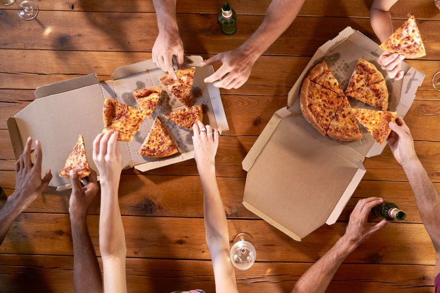 An aerial image of people grabbing slices pizza out of boxes