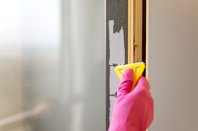 An image of a hand scraping off paint from a door