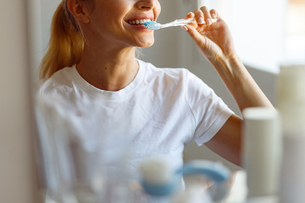 An image of a woman brushing her teeth
