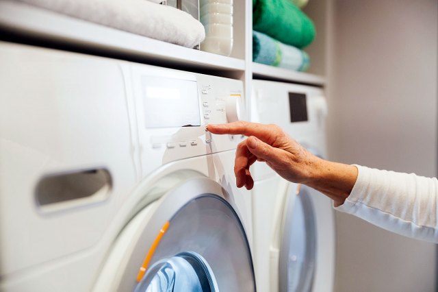 An image of a person pressing a button on a washer