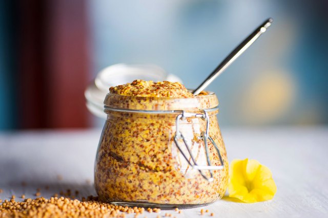 An image of a jar of grainy mustard with a spoon