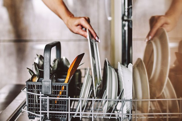 An image of a person loading dishes into a washwasher