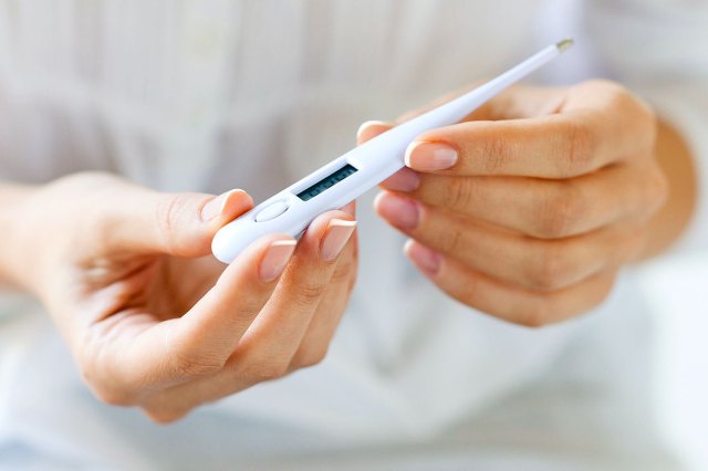 An image of a person holding a thermometer