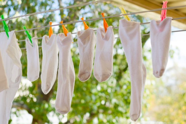 An image of white socks hanging on an outdoor laundry line