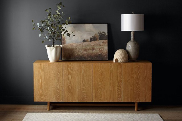 An image of a wooden credenza against a  wall painted in Cracked Pepper by Behr