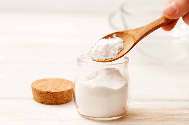 An image of a person spooning baking soda out of a jar