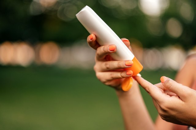 An image of a person squeezing sunscreen onto their finger