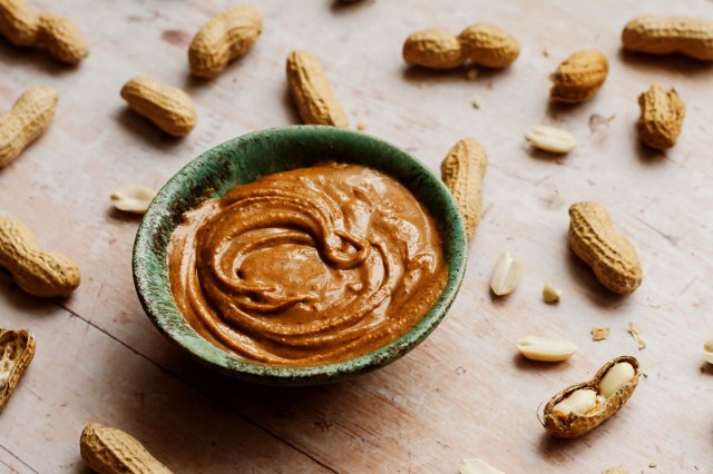 An image of a bowl of peanut butter surrounded by peanuts
