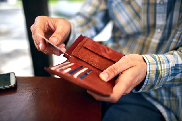 An image of a man taking a credit card out of a red wallet