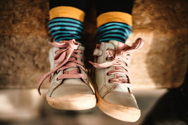 An image of a person wearing white sneakers with blue and yellow socks