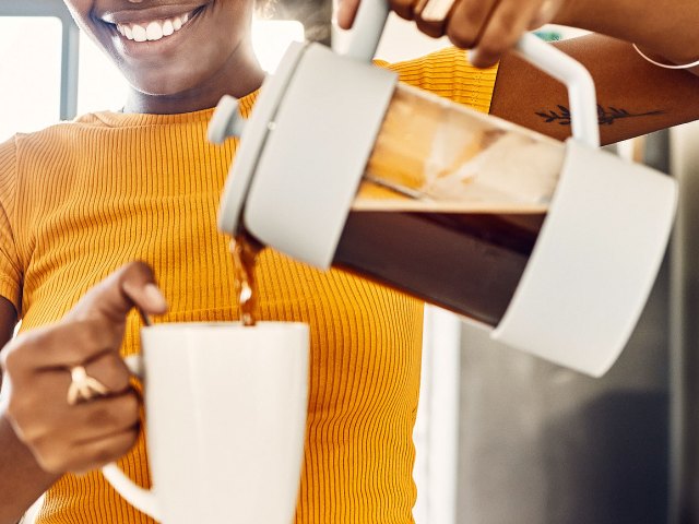 An image of a woman pouring a cup of coffee