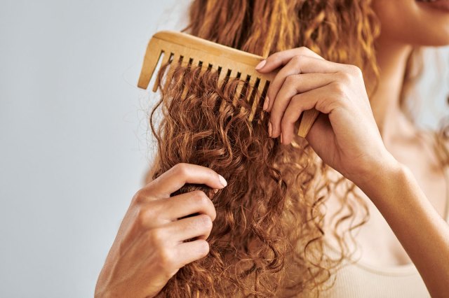 An image of a woman combing her red curly hair