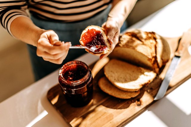 An image of a person spreading jam onto a piece of bread