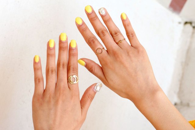 An image of two hands with yellow nail polish