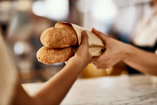 An image of a person handing two loaves of beard to another person