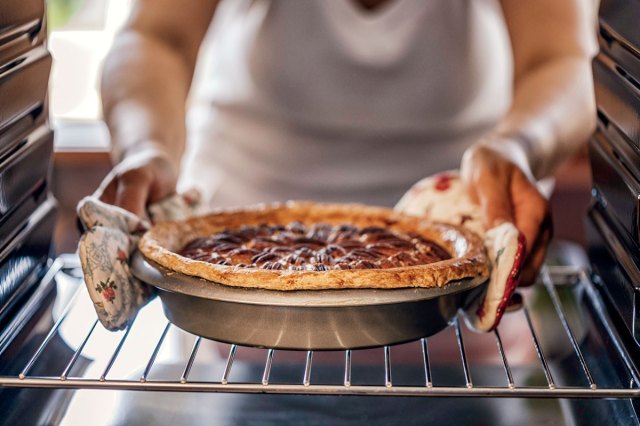 An image of a person pulling a pie out of the oven