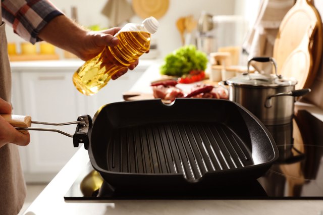 An image of a person holding a grill pan and a bottle of oil