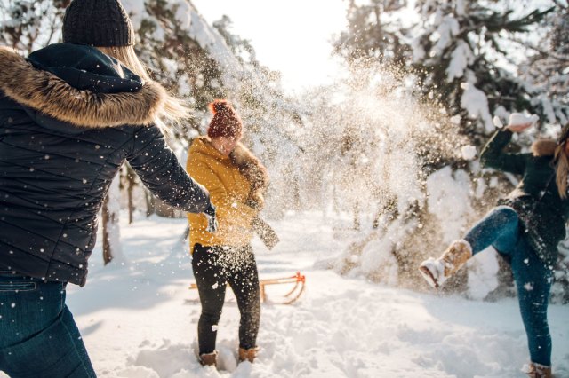 An image of three people throwing snowballs at each other