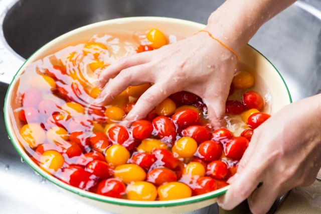 An image of a person washing cherry tomatoes in a bowl