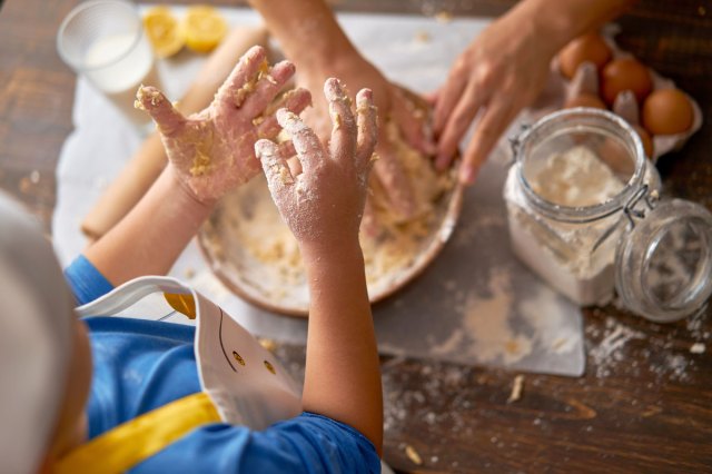 An image of a child and his mother are making a cake at kitchen together